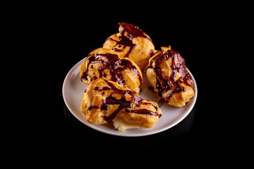 Cake eclair with chocolate icing on a white dish, cup of coffee, chocolate