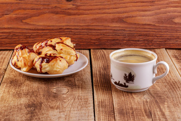 Cake eclair with chocolate icing, cup of coffee, chocolate, on a black background