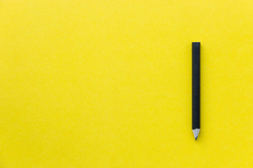 Black pencil on yellow backgroud, minimalist image with creative concept