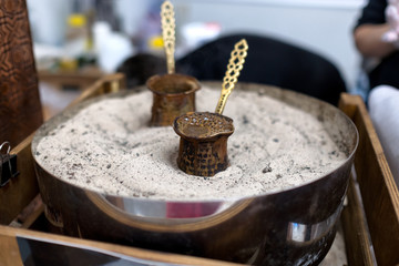 Preparing coffee in coffee jezvas in sand. Turkish method of preparing coffee. Eastern coffee.