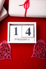 Wooden calendar show of February 14 with red heart and gift boxes.