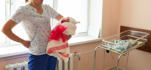 A doctor is holding a beautiful newborn baby in hands. Maternity hospital. A nurse holds a newborn...
