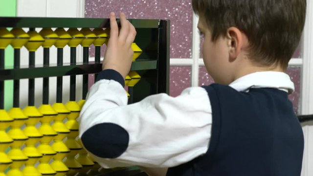 School boy dressed up as teacher holding abacus in a classroom.