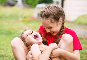 Two Happy little girls embracing and laughing at the park