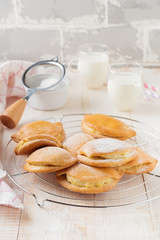 Pasties with cottage cheese and powdered sugar on a light wooden background. Traditional Russian pastry Sochnik. Selective focus. .