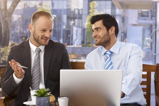 Businessmen discussing ideas on laptop computer