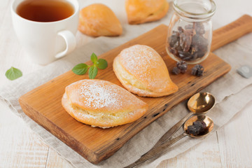 Pasties with cottage cheese and powdered sugar on a light wooden background. Traditional Russian pastry Sochnik. Selective focus. .