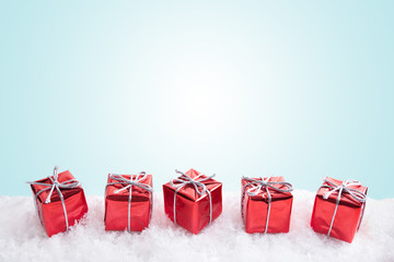 Red gifts on blue background with snow. Copy space. Christmas and New Year.