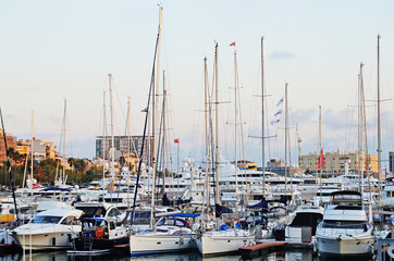 The bay with yachts is surrounded by low hills. Sunset over the bay. Harbor with yachts in Barcelona. Marina for yachts in the Mediterranean.