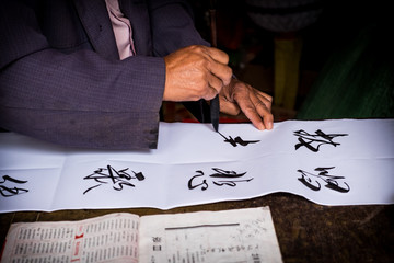 Man is writing with chinese idioms at  Shigu Village or Stone Drum Village, Lijiang, Yunnan...