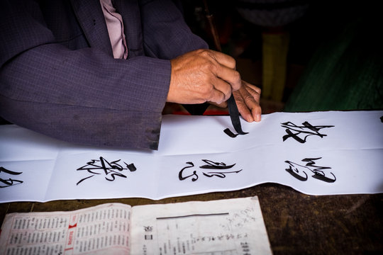 Man is writing with chinese idioms at  Shigu Village or Stone Drum Village, Lijiang, Yunnan Province, China, Asia, Asian, East Asia, Far East