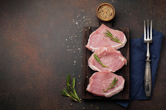 Meat. Raw pieces of pork with rosemary and pepper on a black background. Selective focus. Top view. Place for text.
