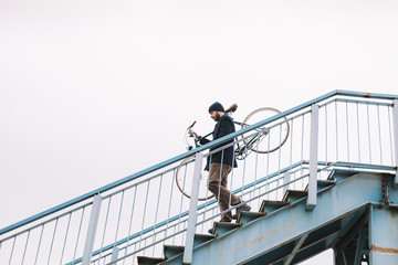 Hipster man carry bicycle down the stairs