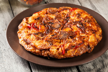Tortilla de patatas. Spanish omelette with sausage chorizo, potatoes, paprika and egg, accompanied by olive oil
