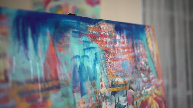 Woman artist painting an abstract painting in the art studio. Close-up paint. artist sprinkles spray bottle on the picture. 4 k