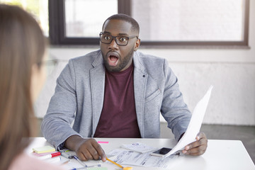 Shocked black businessman studies annual report, surprised with falling sales, realizes that...