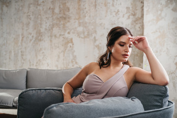 Junge Frau sitzt auf Sofa und ist erschöpft 