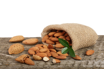 Almonds with leaf in bag from sacking on a wooden table with a white background