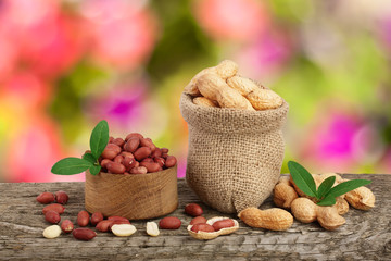 peanuts with leaf in bag on old on wooden table with a blurry garden background