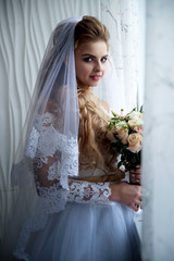 Beautiful young bride posing in a wedding dress at studio