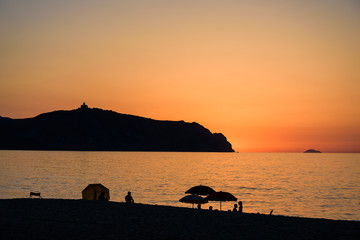 People enjoy Sunset on Bazia beach, Falcone, Sicily. In the background the sanctuary of Tindari