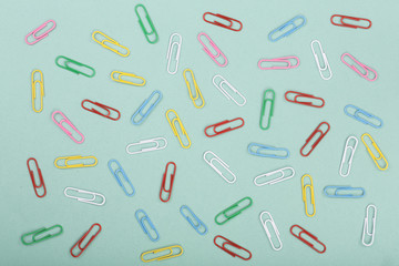 Fototapeta na wymiar colorful paper clips on green background. Top view. Flat lay pattern