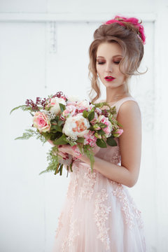 Portrait of an elegant bride with a bouquet of roses in her hands.