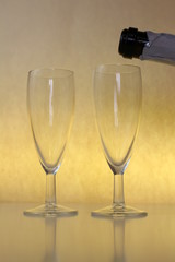 two empty glasses of wine on a yellow background and a bottle of champagne