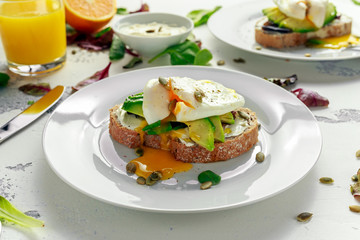 Sandwich, toast with avocado, soft cheese and poached egg on white background