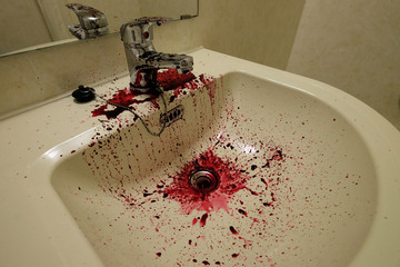 Water sink stained by the red fruit juice and reflection of water tap in the mirror