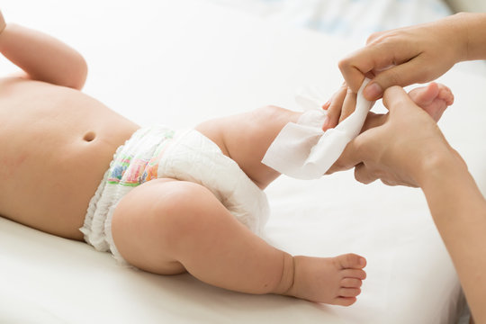 Mother cleaning up and wipes body and leg baby by wet tissue