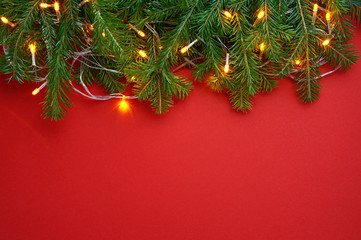 Christmas background decoration with lights and fir tree isolated on red. Top view with blank space.