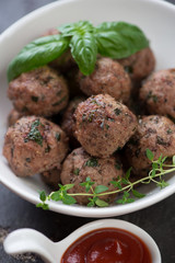 Close-up of baked meatballs with fresh green basil and thyme, selective focus, shallow depth of field