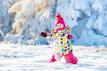 Child playing with snow in winter. Kids outdoors.