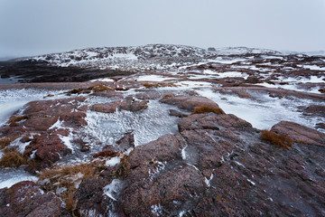 Small old wooden house among the snow-covered rocks