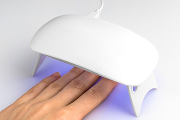 Hand in UV lamp lights for nails on a white background