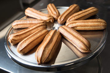 Fresh eclairs lying on a metal tray