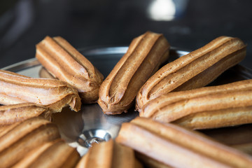 Fresh eclairs lying on a metal tray