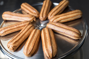 Fresh eclairs lying on a metal tray