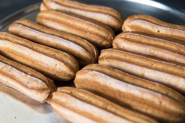 Fresh eclairs lying on a metal tray