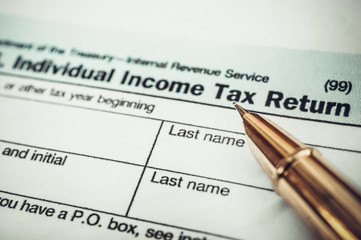Pen pointing on word "tax" on the tax form. Close up. Business concept. Toned image.