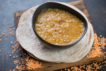 Bowl of masoor dahl or red lentil indian soup with chapati flatbread, horizontal shot