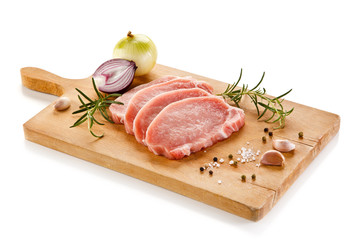 Raw pork chops on cutting board and vegetables