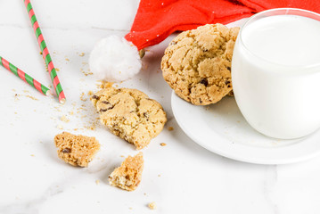 Christmas concept, greeting card. Milk glass and cookies for Santa Claus with Santa's hat on white marble background, copy space © ricka_kinamoto