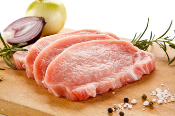 Raw pork chops on cutting board and vegetables