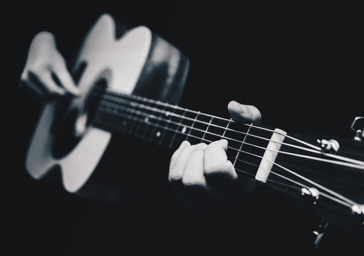 male musician hands playing acoustic guitar, black and white