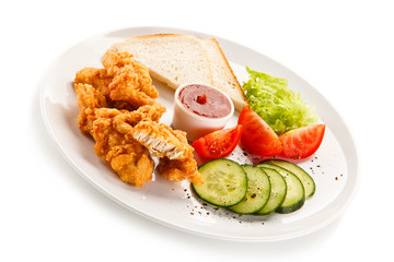 Grilled chicken nuggets and vegetables on white background