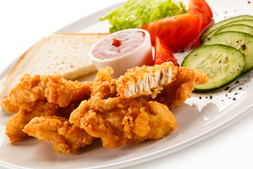 Grilled chicken nuggets and vegetables on white background