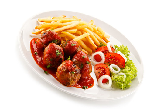 Roasted meatballs, chips and vegetables on white background