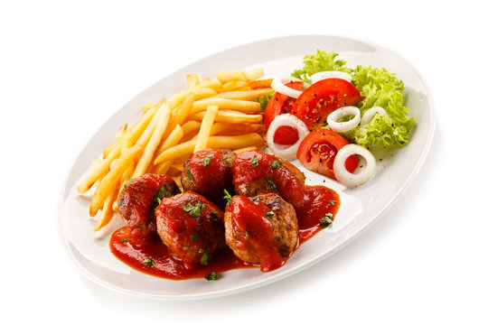 Roasted meatballs, chips and vegetables on white background